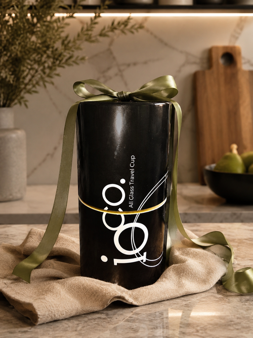 IOco All Glass Travel Coffee Tea Cup in cylindrical black gift box, wrapped in a green bow on a marble bench top. Gift wrapping available at Lorikeet Living