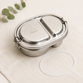Stainless steel Shasta 500ml sealed bento box with two compartments, lid with logo, and spare seal, ideal for food storage, on beige fabric