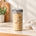Diamond-pressed glass mason jar filled with iced coffee, with a stainless steel lid and clear glass straw, on a cream kitchen bench. Lorikeet Living.