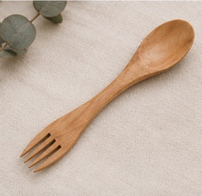 Natural wooden fork with smooth finish, designed for eco-friendly dining, placed on beige linen surface