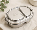 Close-up of stainless steel Shasta bento box with logo on lid, featuring two compartments and secure latch, on neutral background