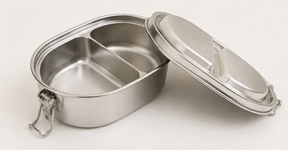Open stainless steel bento box with two divided compartments and lid, perfect for lunch or meal prep, on beige surface